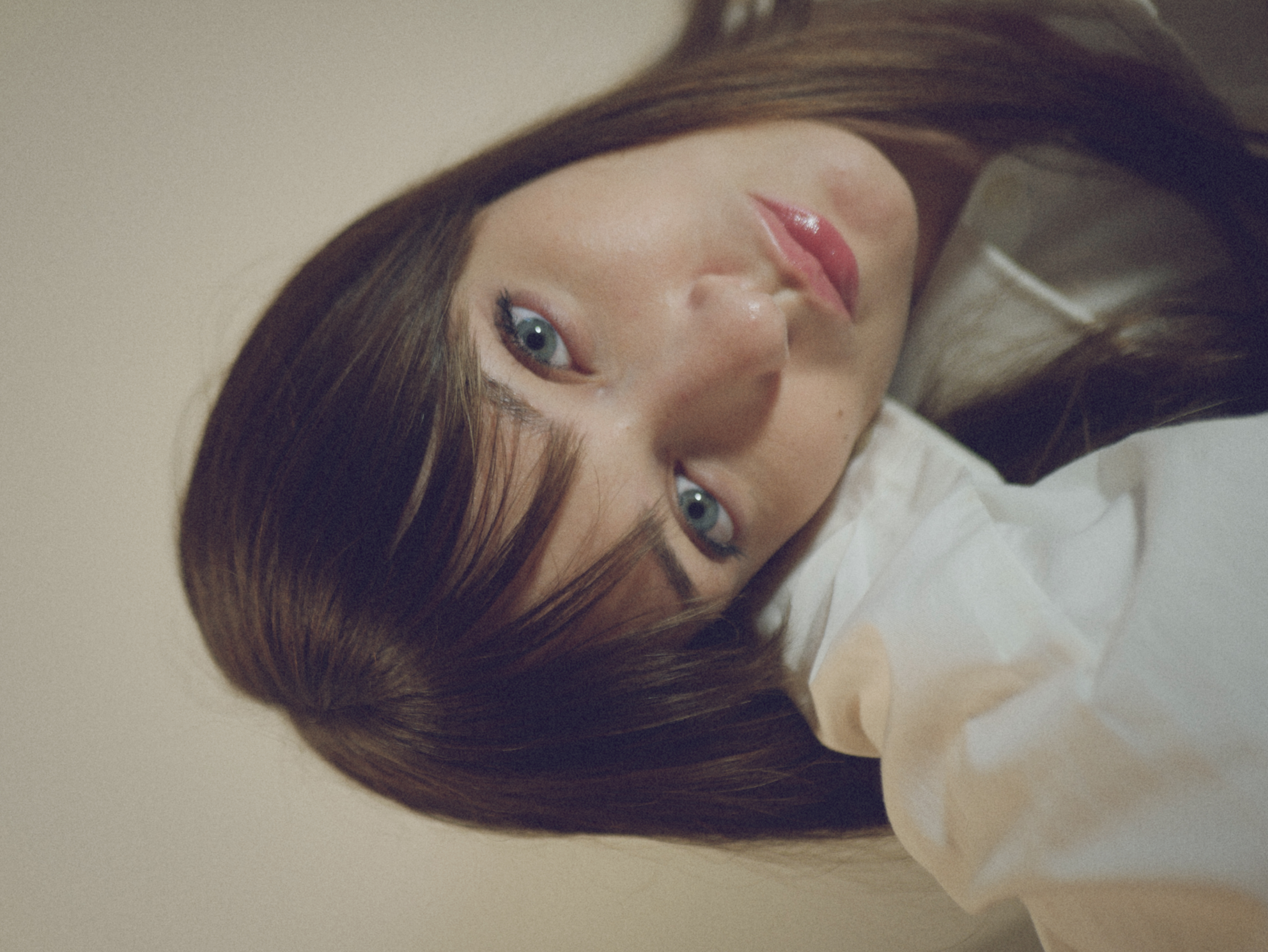 Kris Brouillette resting her head against her sleeve, eyes lowered, in an oversized white shirt